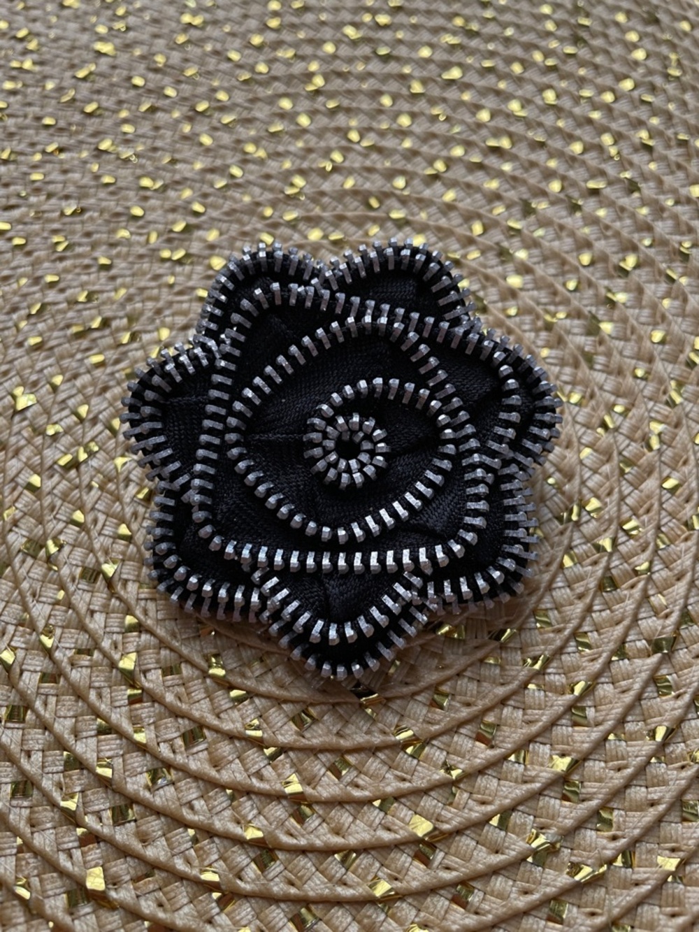Black and silver brooch in shape of a flower. Fabric with metal trim